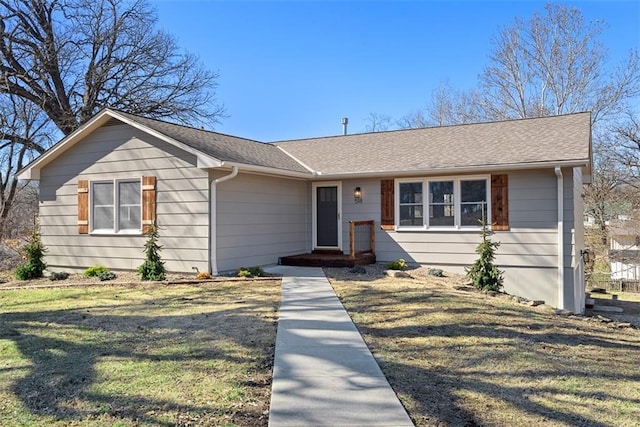 view of front of home featuring a front lawn and roof with shingles