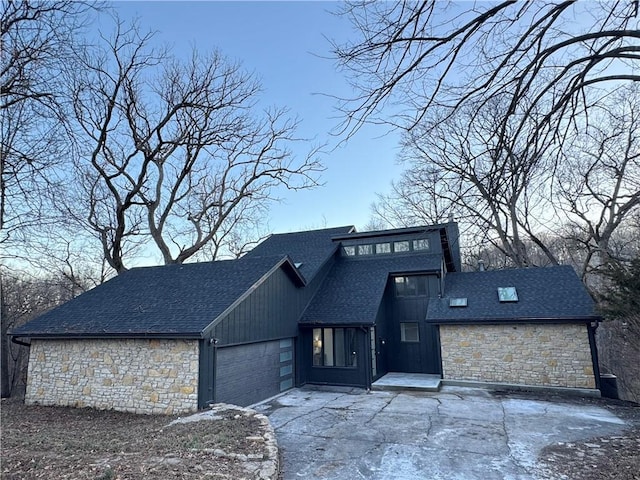 view of front of property with a garage, driveway, a shingled roof, and stone siding