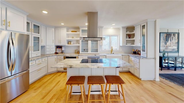 kitchen featuring island range hood, a kitchen island, a sink, freestanding refrigerator, and open shelves