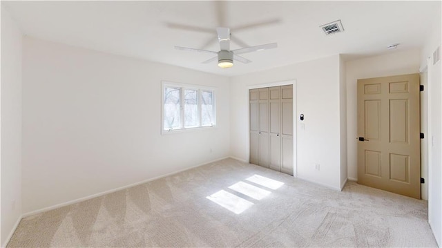 unfurnished bedroom with a ceiling fan, light colored carpet, a closet, and visible vents