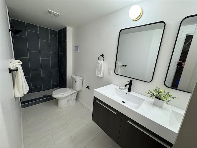 full bathroom featuring double vanity, visible vents, tiled shower, toilet, and a sink