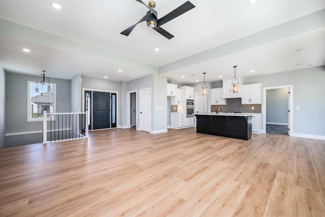 unfurnished living room with baseboards, recessed lighting, and light wood-style floors