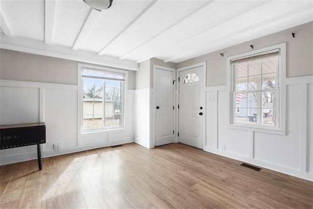 entrance foyer with visible vents, wainscoting, beamed ceiling, wood finished floors, and a decorative wall