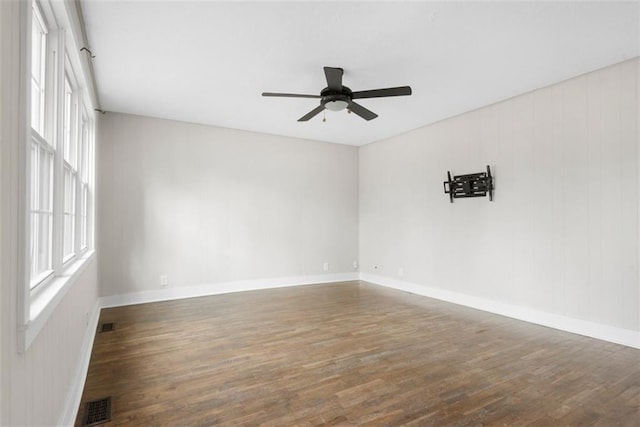 unfurnished room featuring a ceiling fan, baseboards, visible vents, and wood finished floors