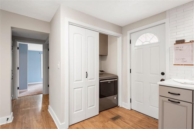 kitchen with light wood finished floors, stove, visible vents, and gray cabinetry