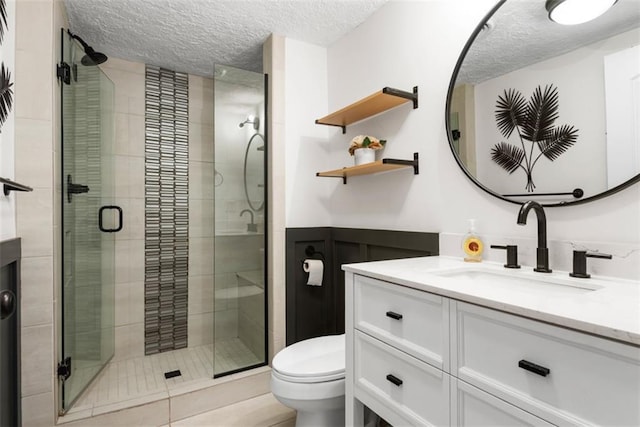 bathroom featuring toilet, a stall shower, a textured ceiling, and vanity