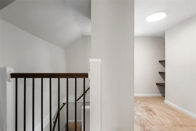 staircase with carpet, lofted ceiling, baseboards, and a textured ceiling