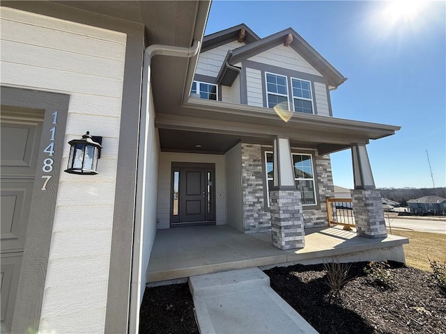 view of exterior entry featuring stone siding and a porch