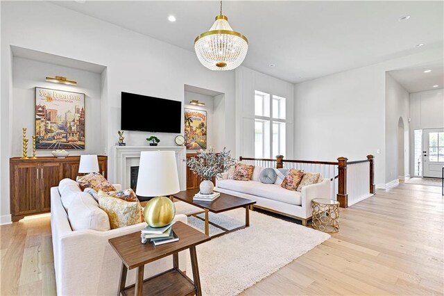 living room featuring arched walkways, recessed lighting, a fireplace, baseboards, and light wood-style floors