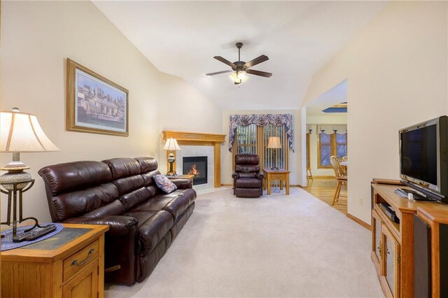 living room featuring ceiling fan, light carpet, baseboards, vaulted ceiling, and a tiled fireplace