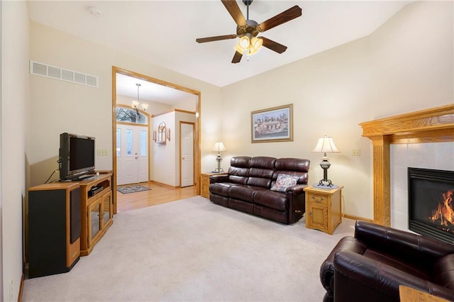 living room featuring a fireplace, light colored carpet, visible vents, baseboards, and ceiling fan with notable chandelier