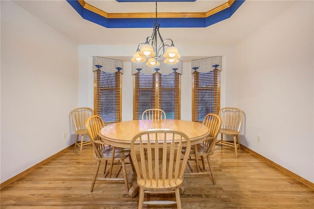 dining area featuring baseboards, a tray ceiling, wood finished floors, and a notable chandelier