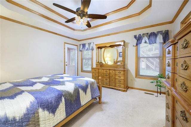 bedroom with light carpet, a ceiling fan, baseboards, a tray ceiling, and crown molding