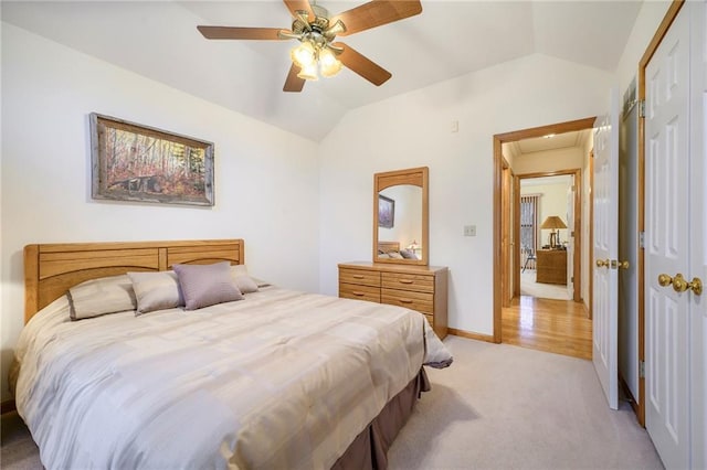 bedroom featuring light carpet, baseboards, ceiling fan, vaulted ceiling, and a closet