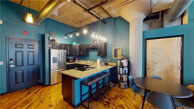 kitchen featuring black appliances, a high ceiling, a peninsula, and wood finished floors