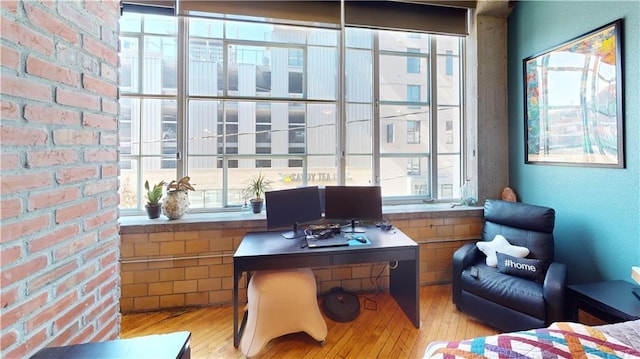 office space with brick wall and wood finished floors