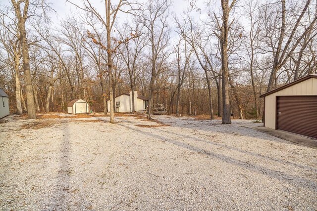 view of yard with a shed, a detached garage, and an outbuilding