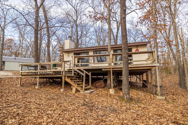 rear view of property featuring a chimney, stairway, and a deck