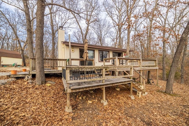 back of house with a chimney and a wooden deck