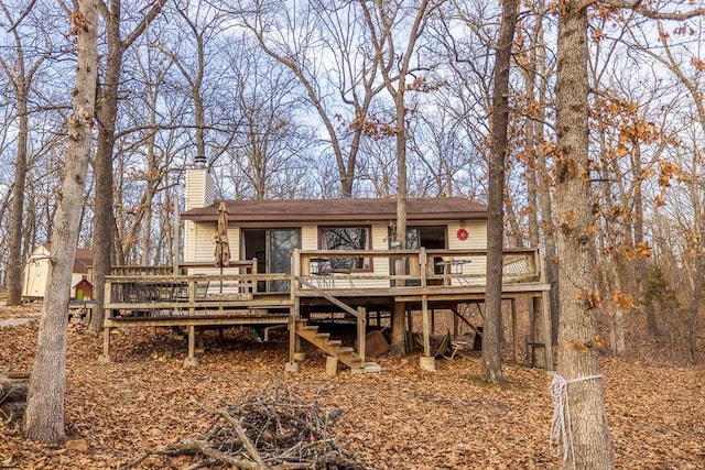 back of property featuring stairway, a chimney, and a wooden deck