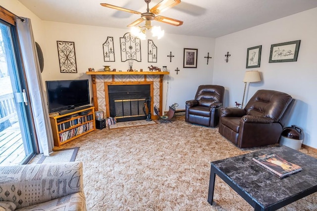 living area with carpet, a tiled fireplace, a ceiling fan, and baseboards