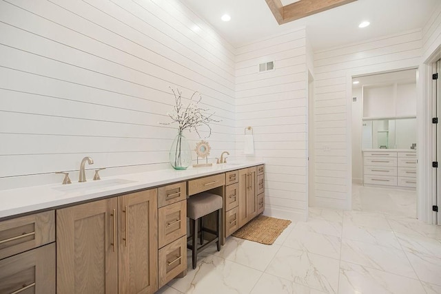 bathroom featuring marble finish floor, visible vents, a sink, and double vanity