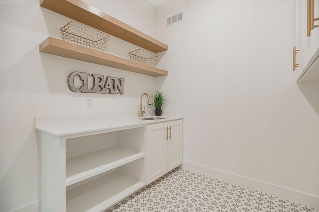 interior details with baseboards, a sink, visible vents, and tile patterned floors