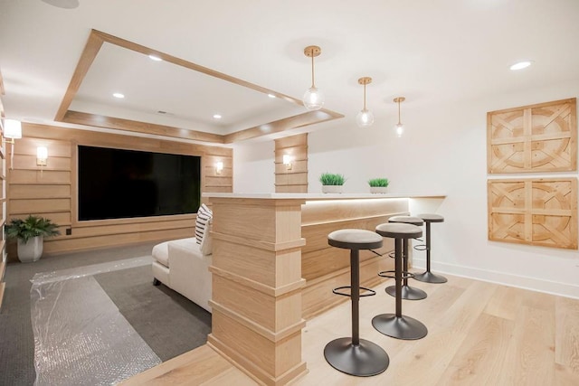 bar featuring baseboards, a tray ceiling, wood finished floors, and recessed lighting