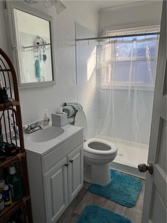 full bathroom with toilet, wood finished floors, vanity, a stall shower, and crown molding