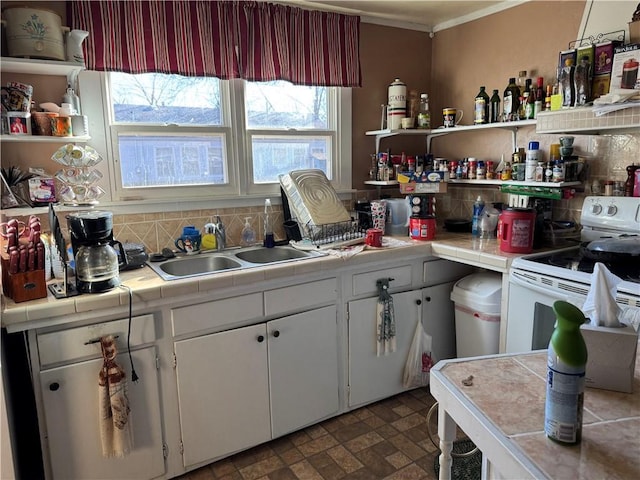 kitchen featuring tile countertops, white range with electric cooktop, tasteful backsplash, open shelves, and a sink