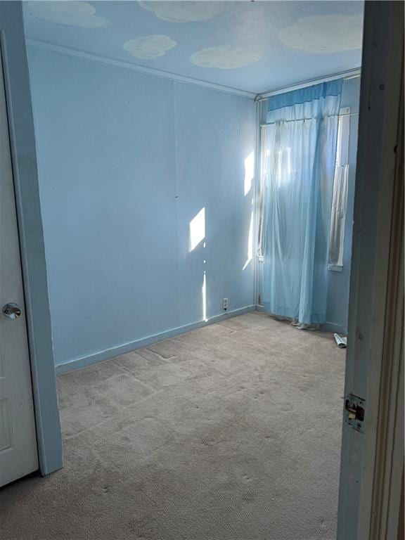 carpeted empty room featuring ornamental molding and baseboards