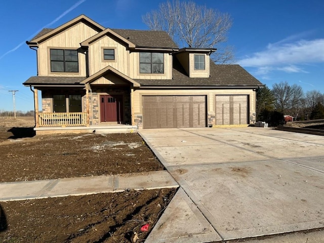 view of front of house featuring a garage, concrete driveway, stone siding, roof with shingles, and covered porch