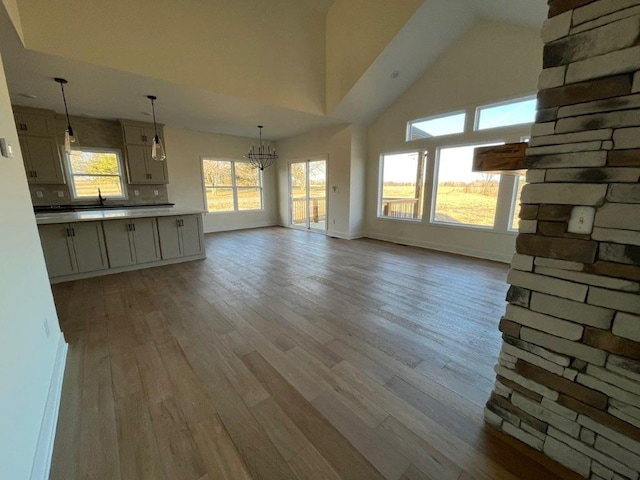 unfurnished living room featuring a notable chandelier, a towering ceiling, baseboards, and wood finished floors