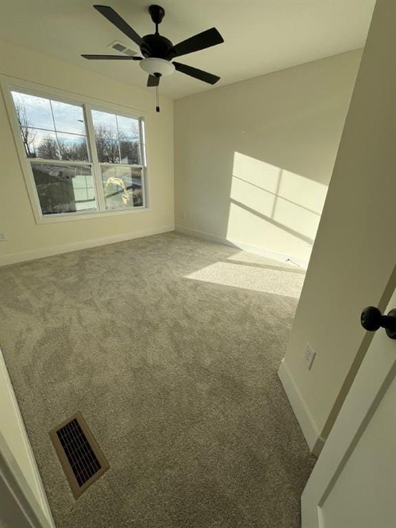 unfurnished room with carpet, visible vents, and baseboards