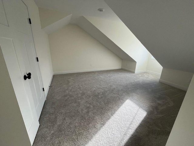 additional living space with baseboards, vaulted ceiling, and carpet flooring