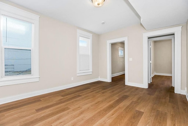 spare room with baseboards and wood finished floors