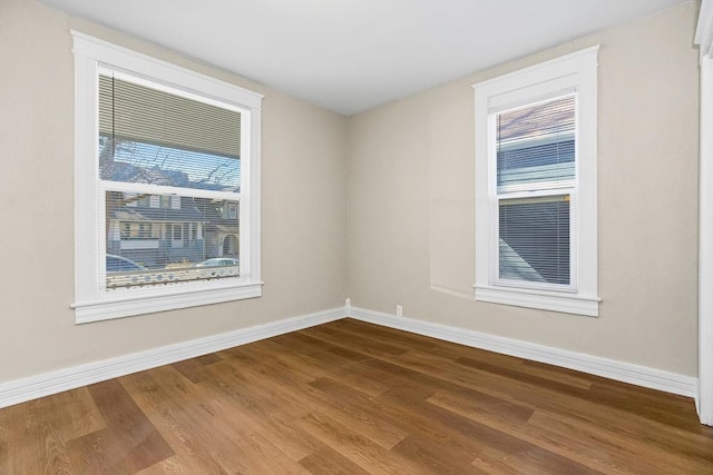 spare room with baseboards and dark wood-style flooring