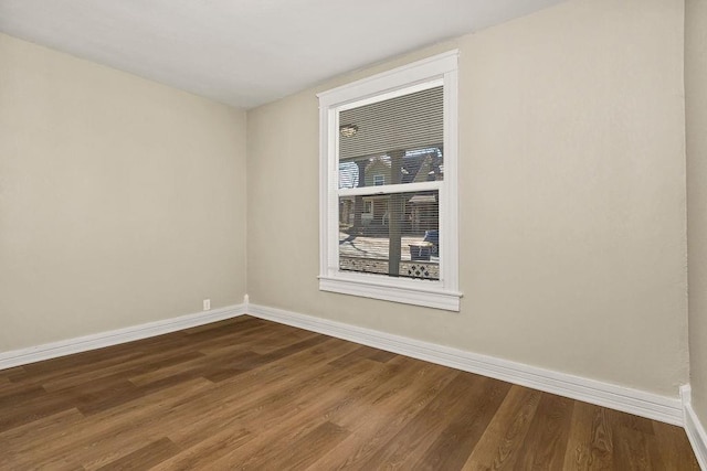 empty room featuring baseboards and dark wood-style flooring