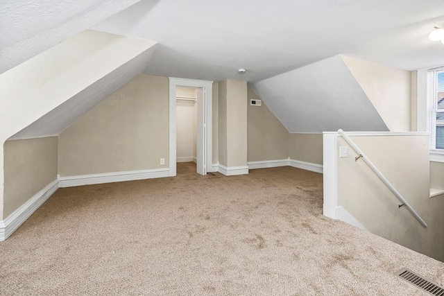 additional living space featuring vaulted ceiling, carpet flooring, visible vents, and baseboards