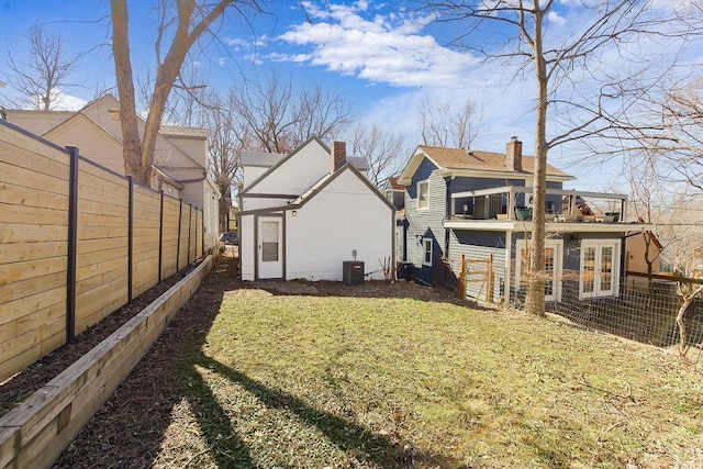 view of yard featuring central air condition unit, a fenced backyard, and french doors