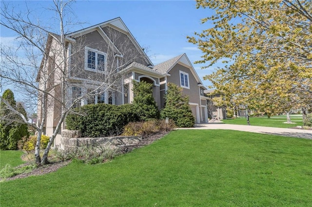 view of front of property with driveway, a garage, stucco siding, and a front lawn