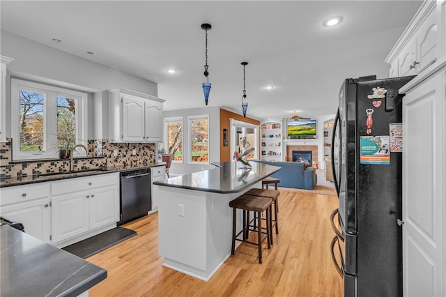 kitchen with black appliances, a sink, dark countertops, white cabinets, and recessed lighting
