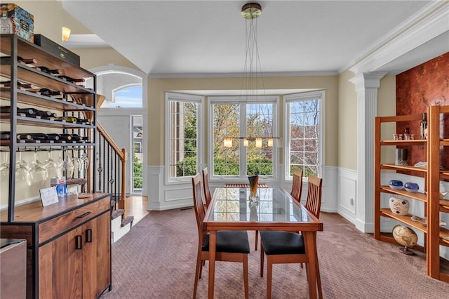 dining space with carpet, stairs, a wainscoted wall, healthy amount of natural light, and ornamental molding