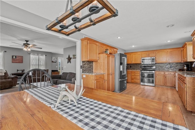 kitchen with open floor plan, backsplash, stainless steel appliances, and a sink