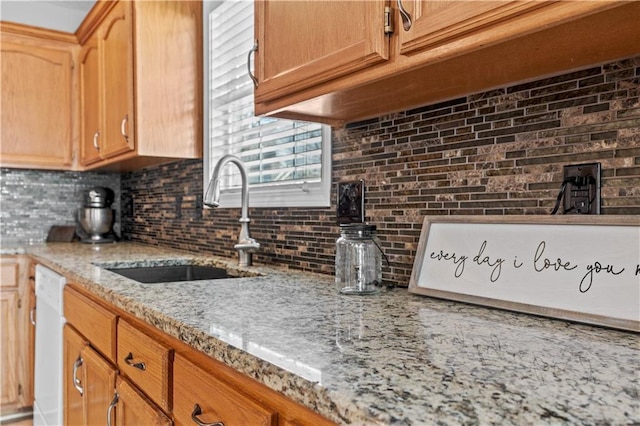 kitchen featuring a sink, light stone countertops, tasteful backsplash, and white dishwasher