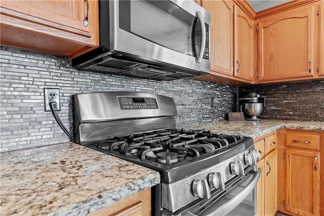 kitchen featuring backsplash, stainless steel appliances, and light stone countertops