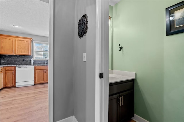 bathroom with vanity, wood finished floors, baseboards, decorative backsplash, and a textured ceiling