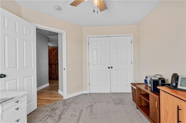 interior space featuring a closet, light carpet, baseboards, and ceiling fan