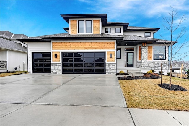 prairie-style home with a garage, stone siding, a front lawn, and driveway