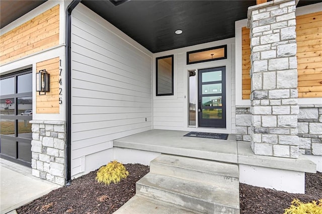 view of exterior entry featuring stone siding and covered porch